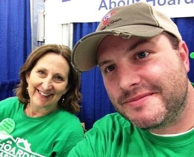 Two MNHTF volunteers in green shirts at an outreach booth