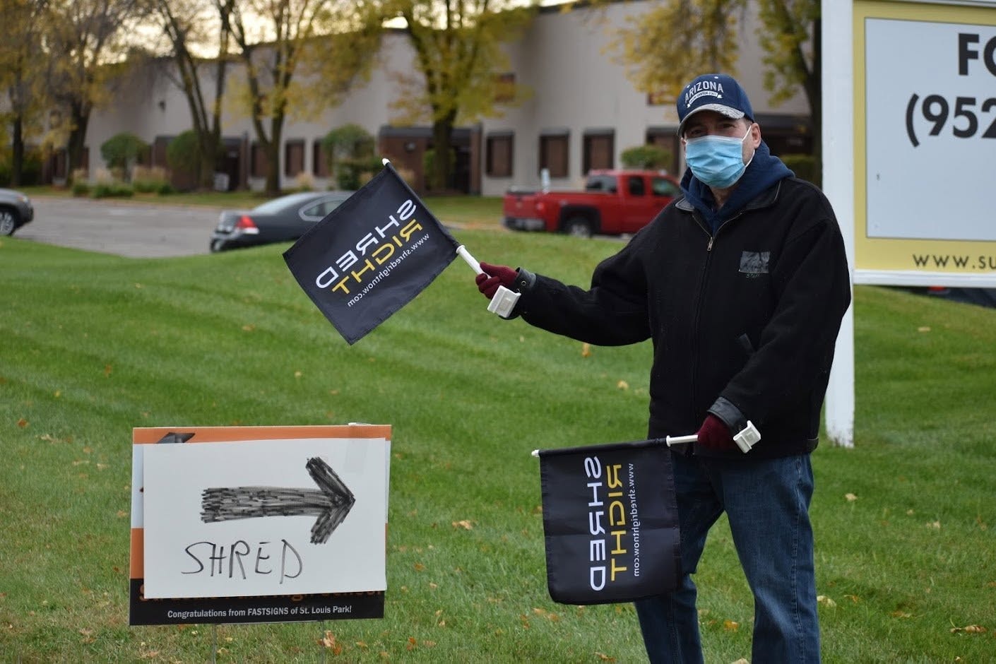 Volunteer holding Shred Right flags next to directional shred sign